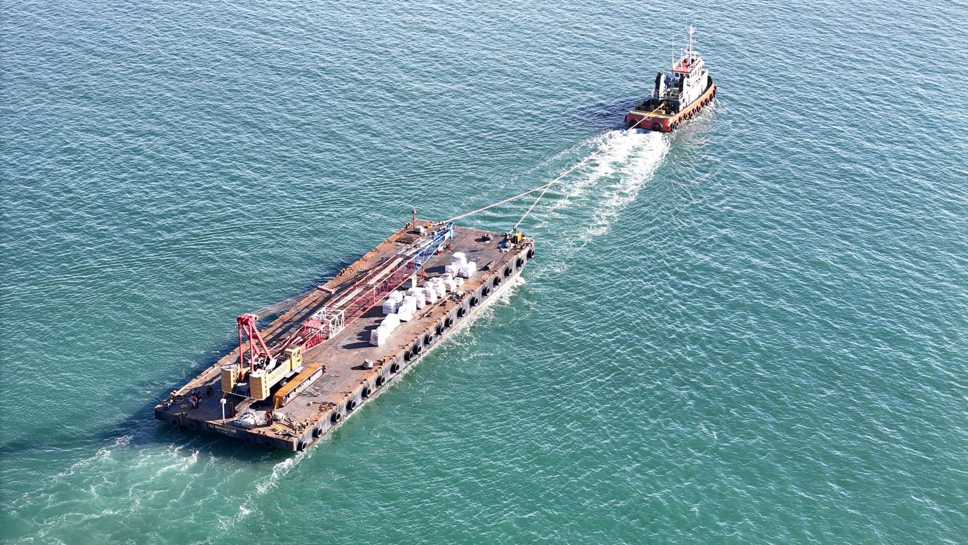 Tug towing a loaded flat-top barge
